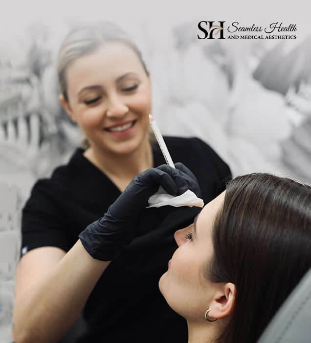 Smiling Seamless Health nurse injector marking a patient's face