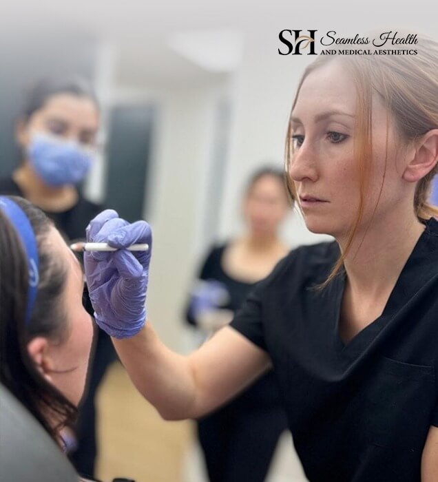 Instructor in scrubs demonstrating an injection technique to a training participant