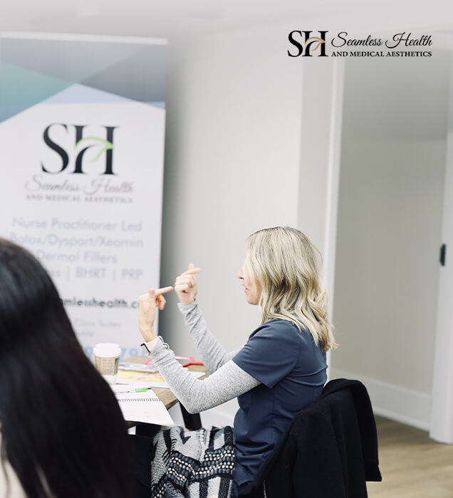 Instructor speaking with participants in front of a Seamless Health banner during training